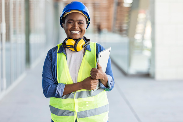 young African American woman smiling while wearing a hard hat and neon safety vest