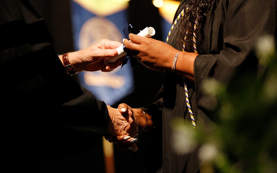 Close up of a CSU graduate shaking hands and accepting diploma during commencement