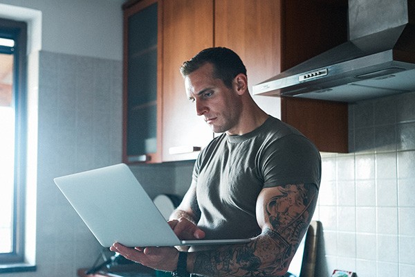 military service member works on a laptop in a kitchen