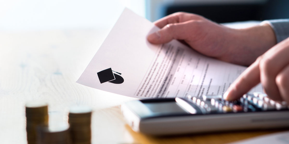 close up image of one hand holding a financial aid document and one hand pushing buttons on a calculator