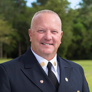 Caucasian man with close cropped blonde hair wearing Fire Chief's dress uniform.