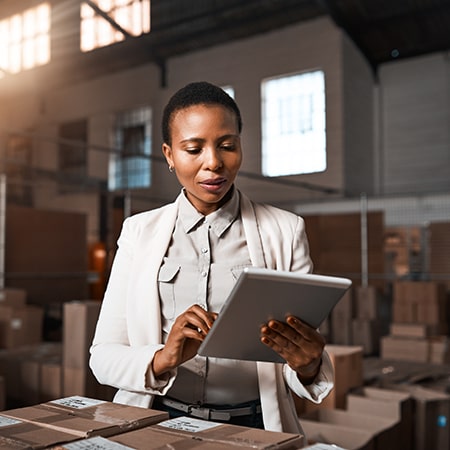 Woman with handheld device managing supplies at warehouse facility